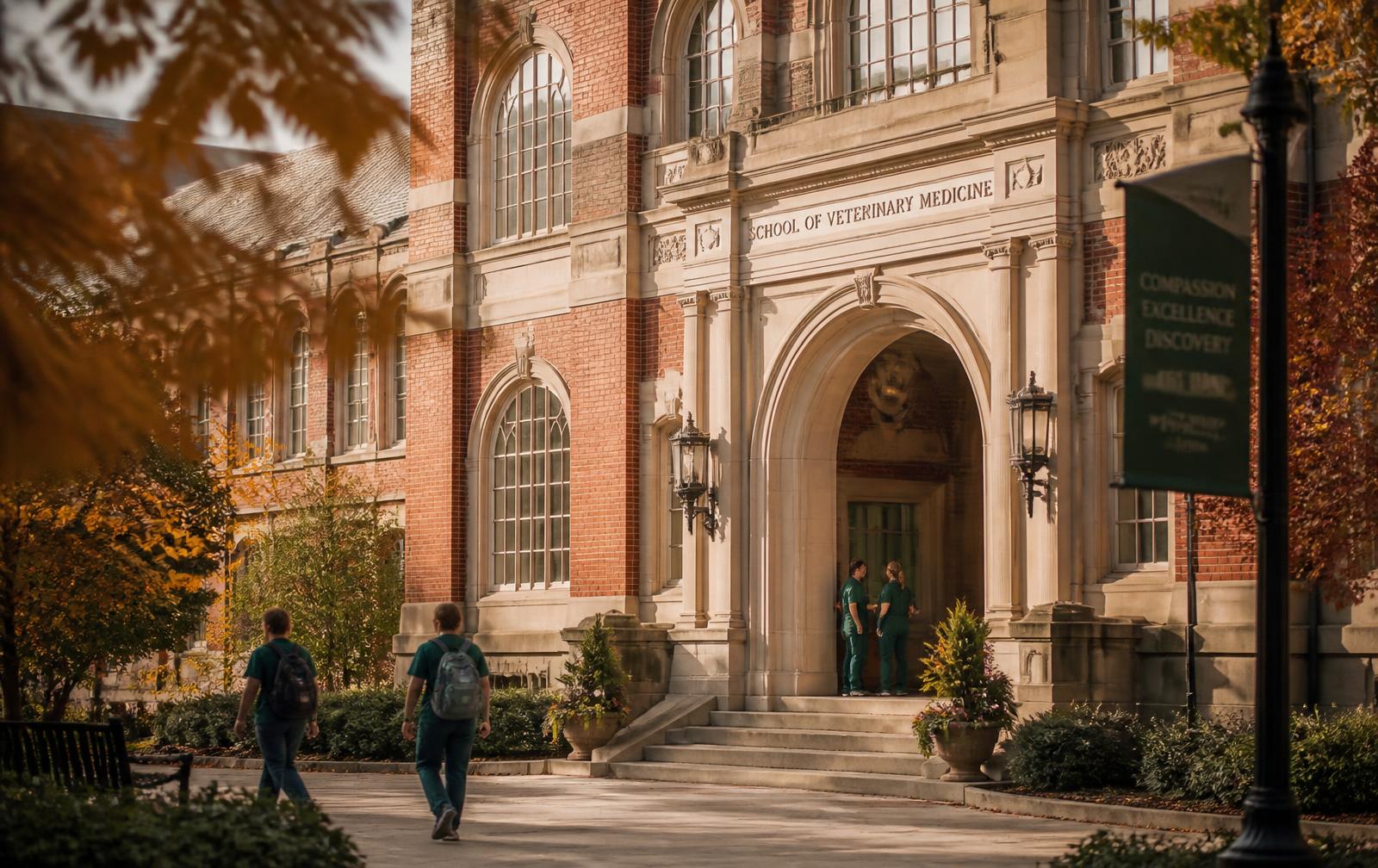 Ivy League veterinary school building with arched stone entrance and students walking past in autumn light